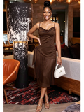 Model wearing a chocolate brown satin cowl neck midi dress with fringe hem, side-tie waist detail, and spaghetti straps, styled with gold strappy heels and a white mini bag